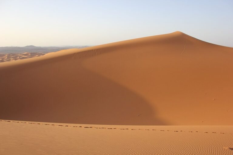 A single tall sand dune under a pale sky in the Sahara near Merzouga, Morocco